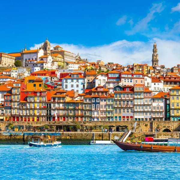 Colorful buildings line the Douro River in Porto, Portugal, with boats on the water.